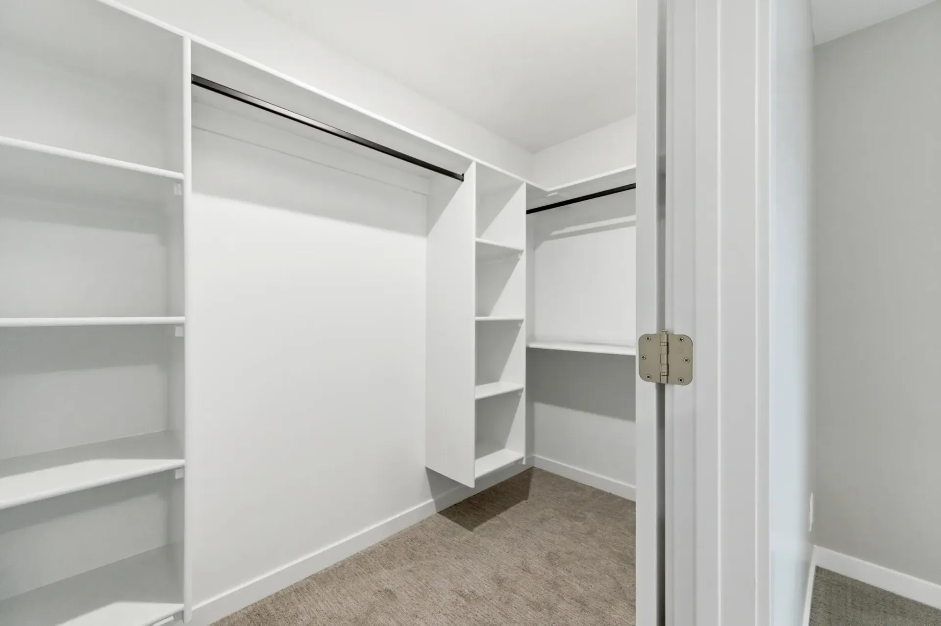 White walk-in closet with built-in shelves and hanging rods.