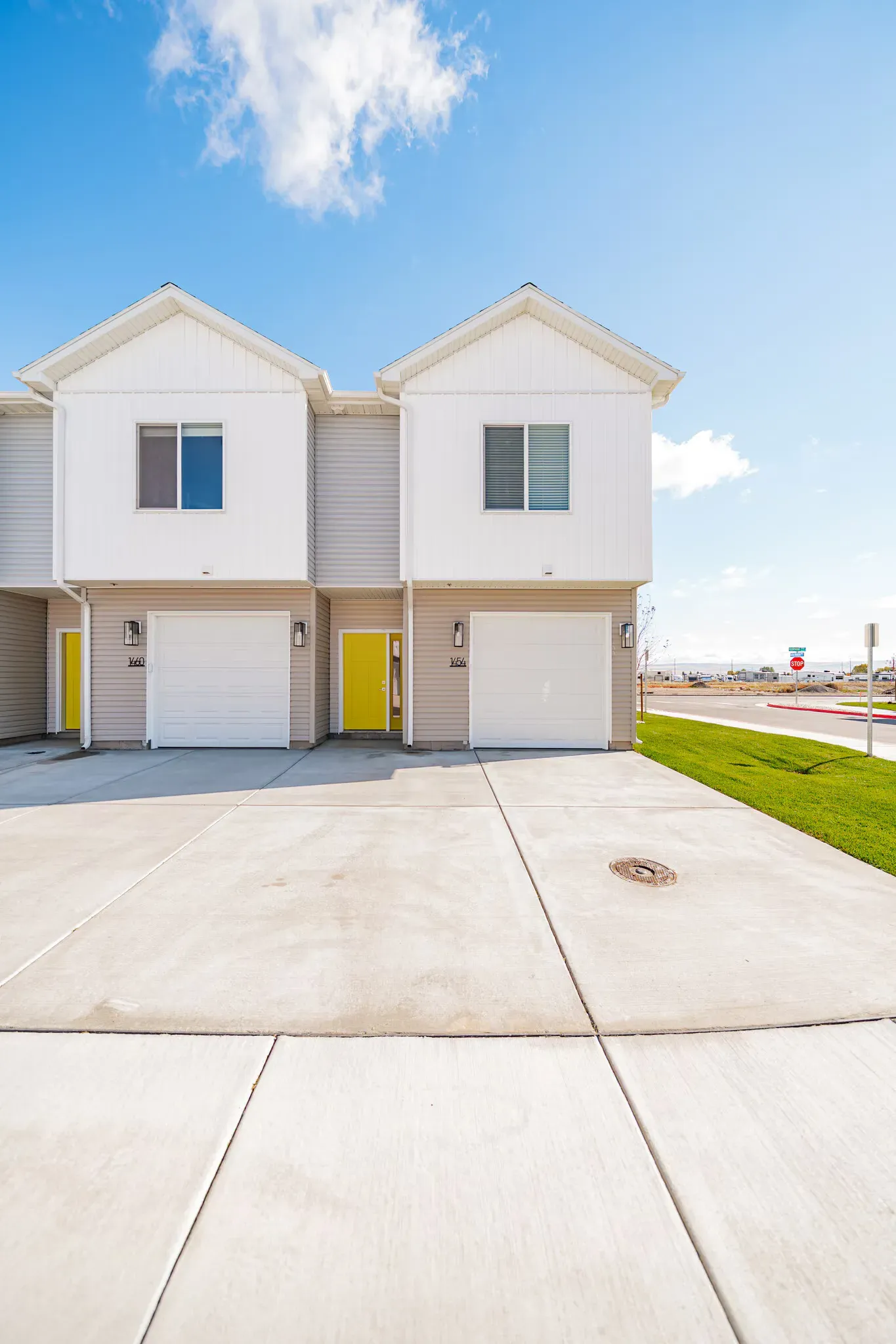 Exterior view of two-story townhome buildings with attached garages and yellow entry doors.