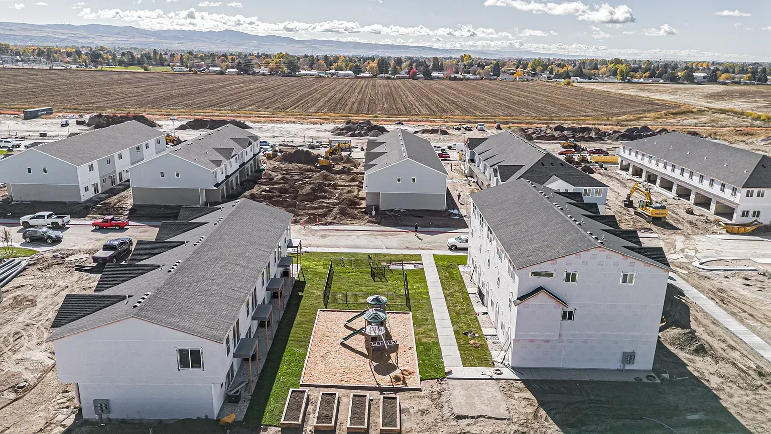 Aerial view of a developing apartment community with white buildings and a central playground.