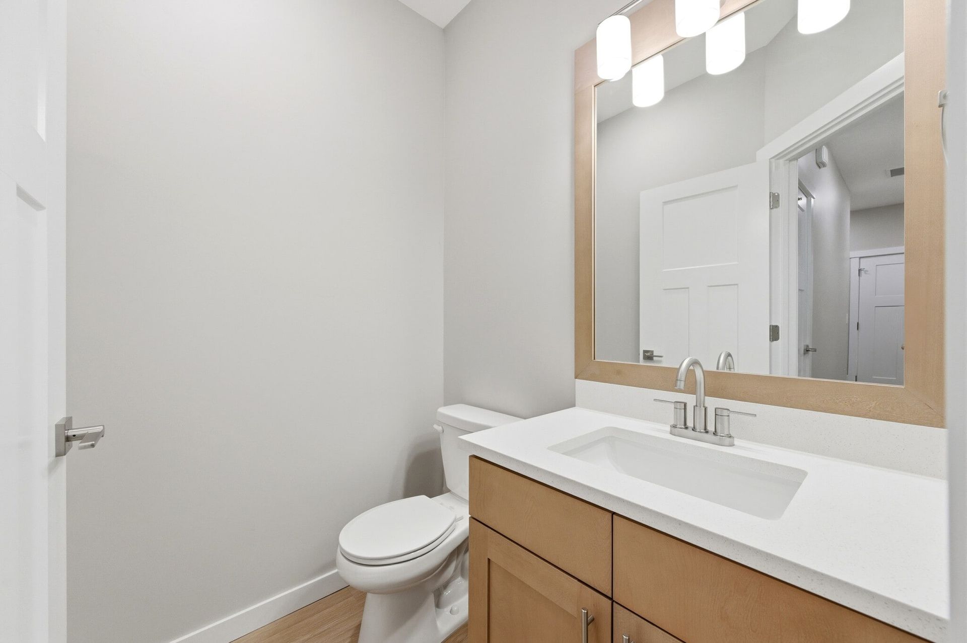 Bathroom vanity with sink, mirror, and toilet in a modern apartment.
