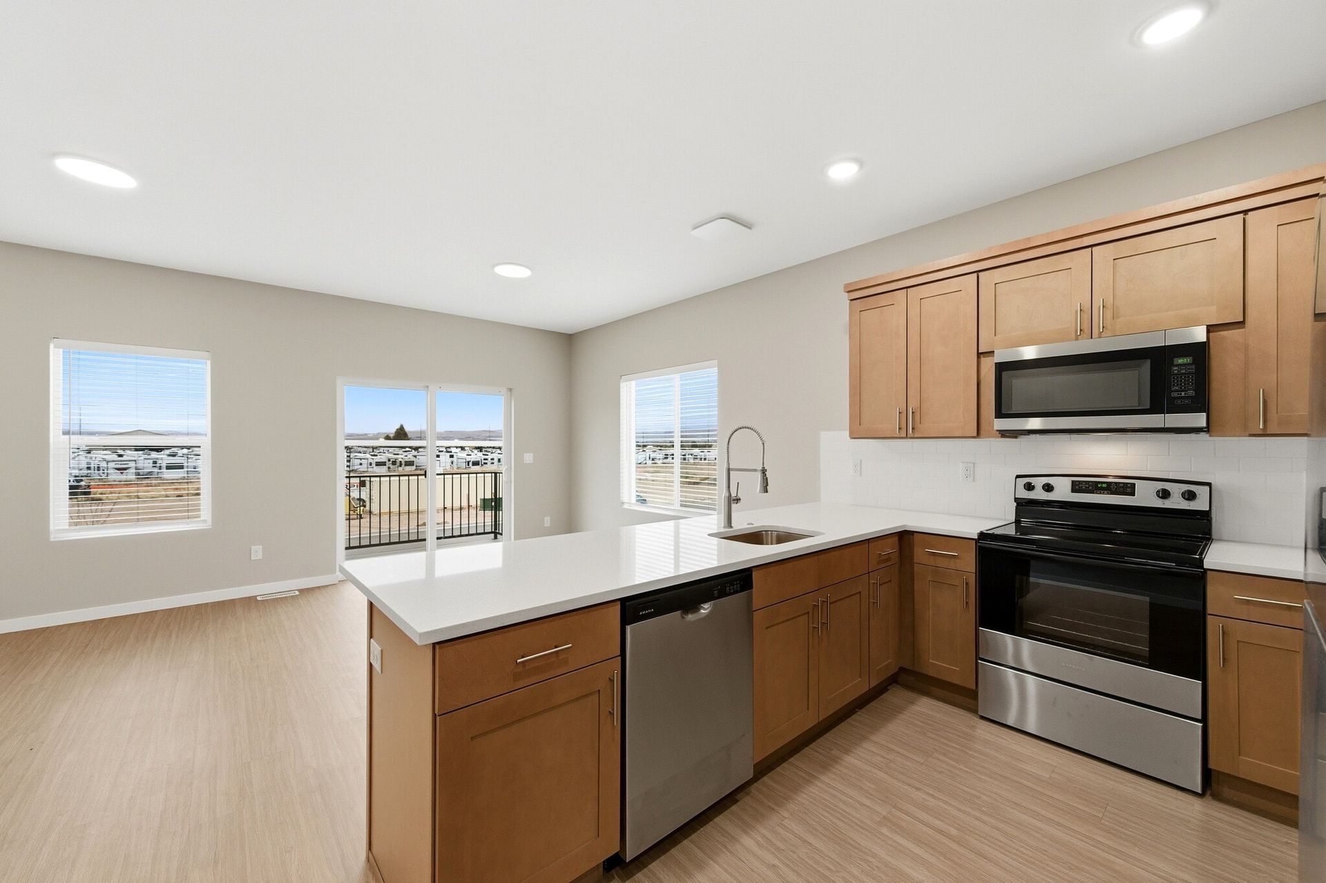 Open-concept kitchen with an island, stainless-steel appliances, and a sliding door to a balcony.