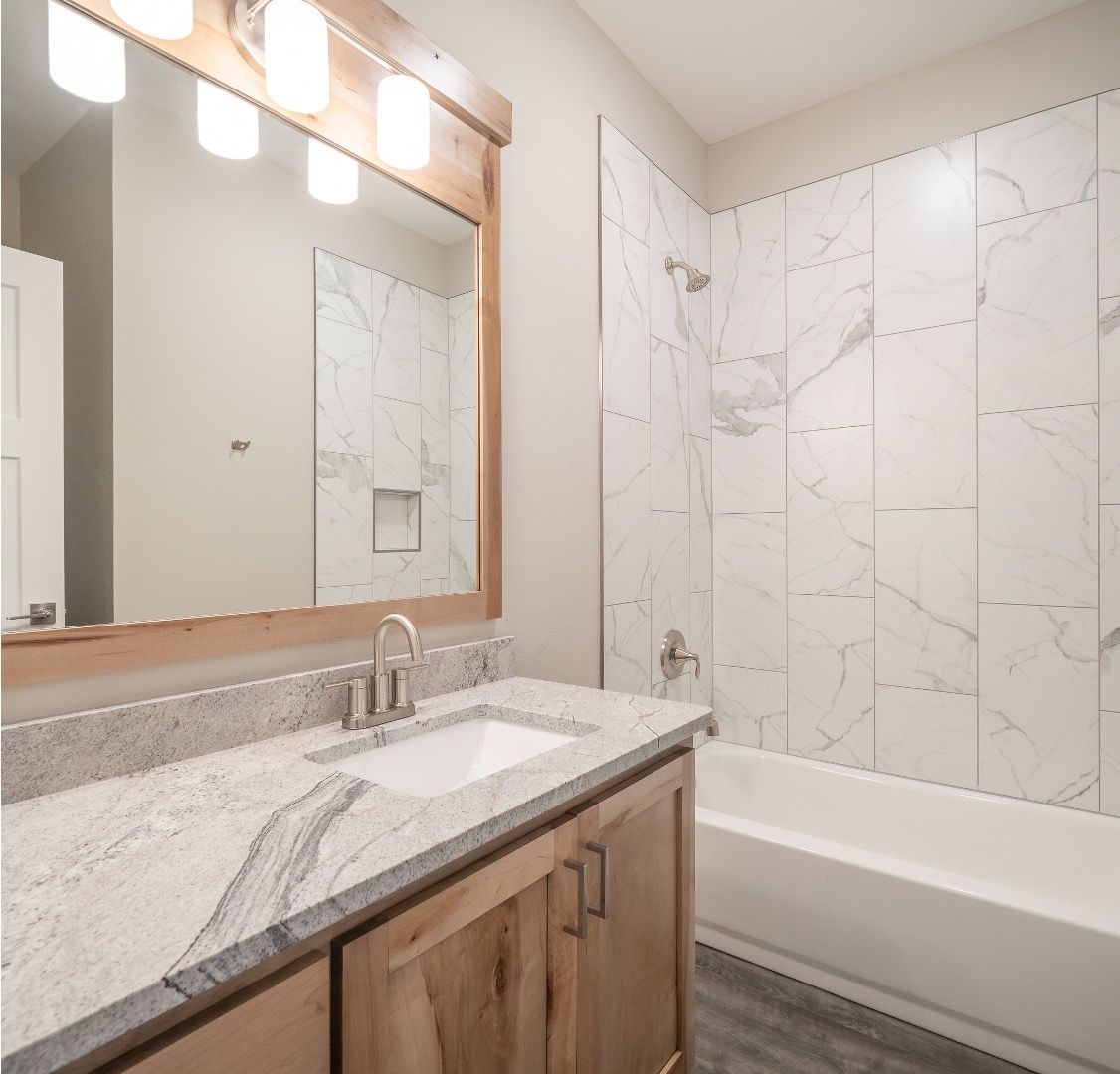 Bathroom with marble-patterned tiles, granite countertop, and a wooden vanity.
