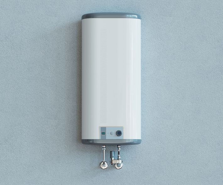 White water heater on a light blue textured wall, with silver pipes extending below.