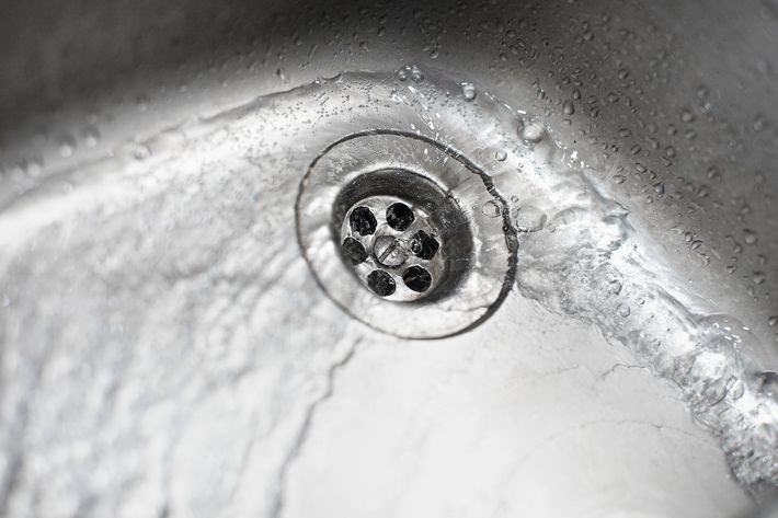 Water flows into a metal sink, over the drain.