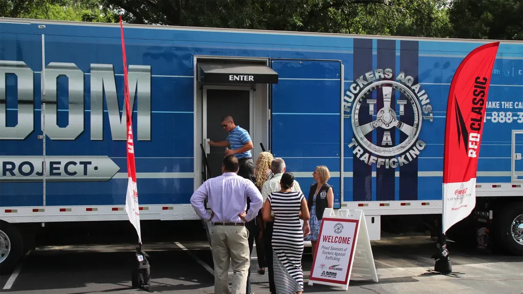 Blue University of Liverpool project truck with people standing outside, banners and a signboard by the door