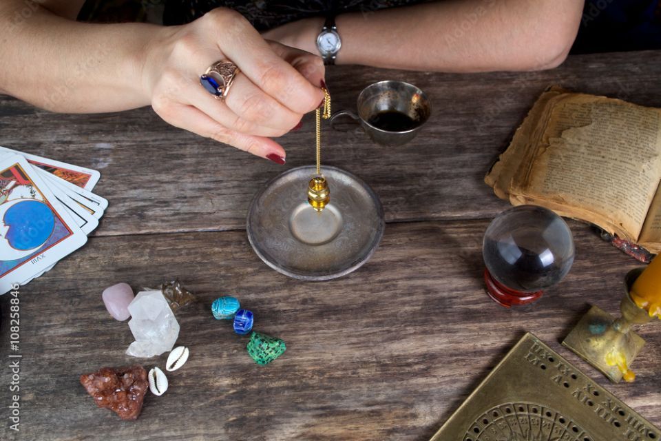 a pendulum over the hand, healing or oracle foretelling, candles, runes and healing stones