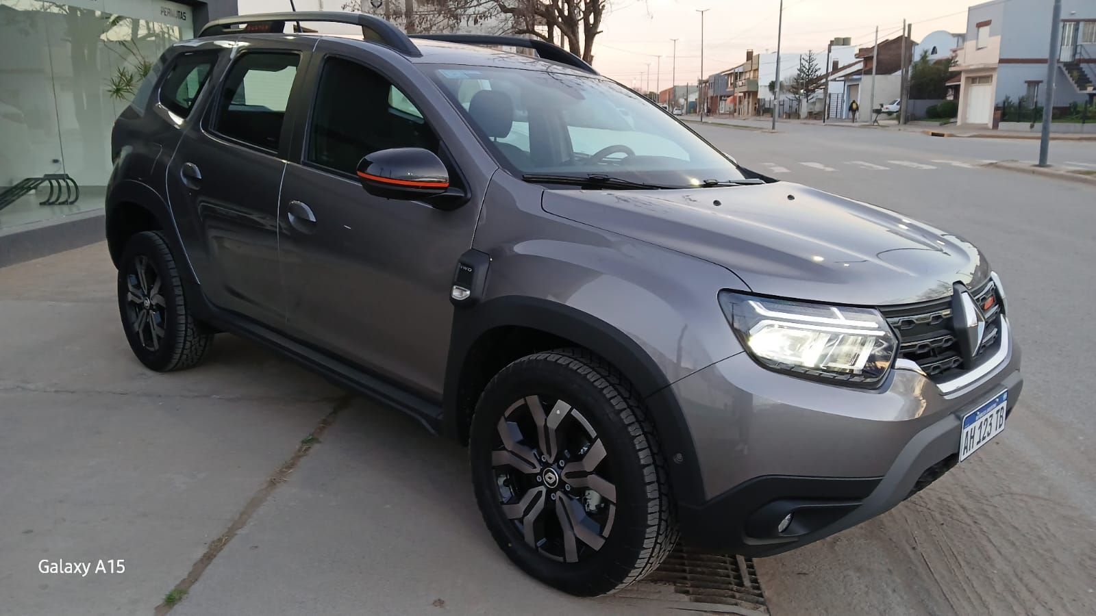 Vehículo utilitario deportivo Renault Duster de color gris estacionado frente a un edificio.