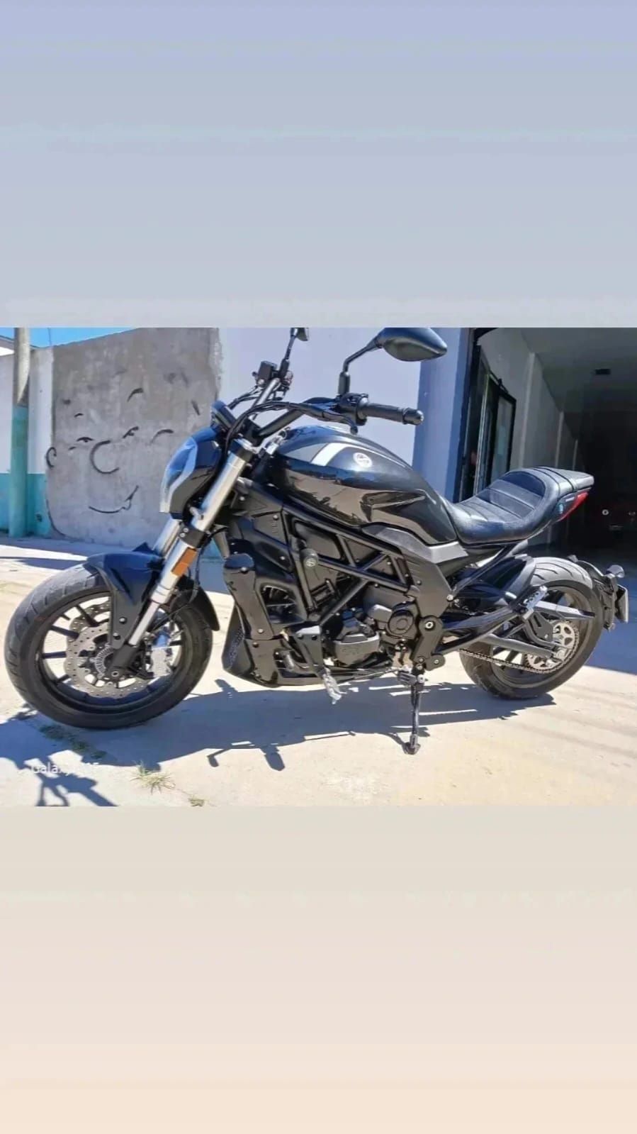 Motocicleta Benelli negra estacionada afuera en un día soleado.