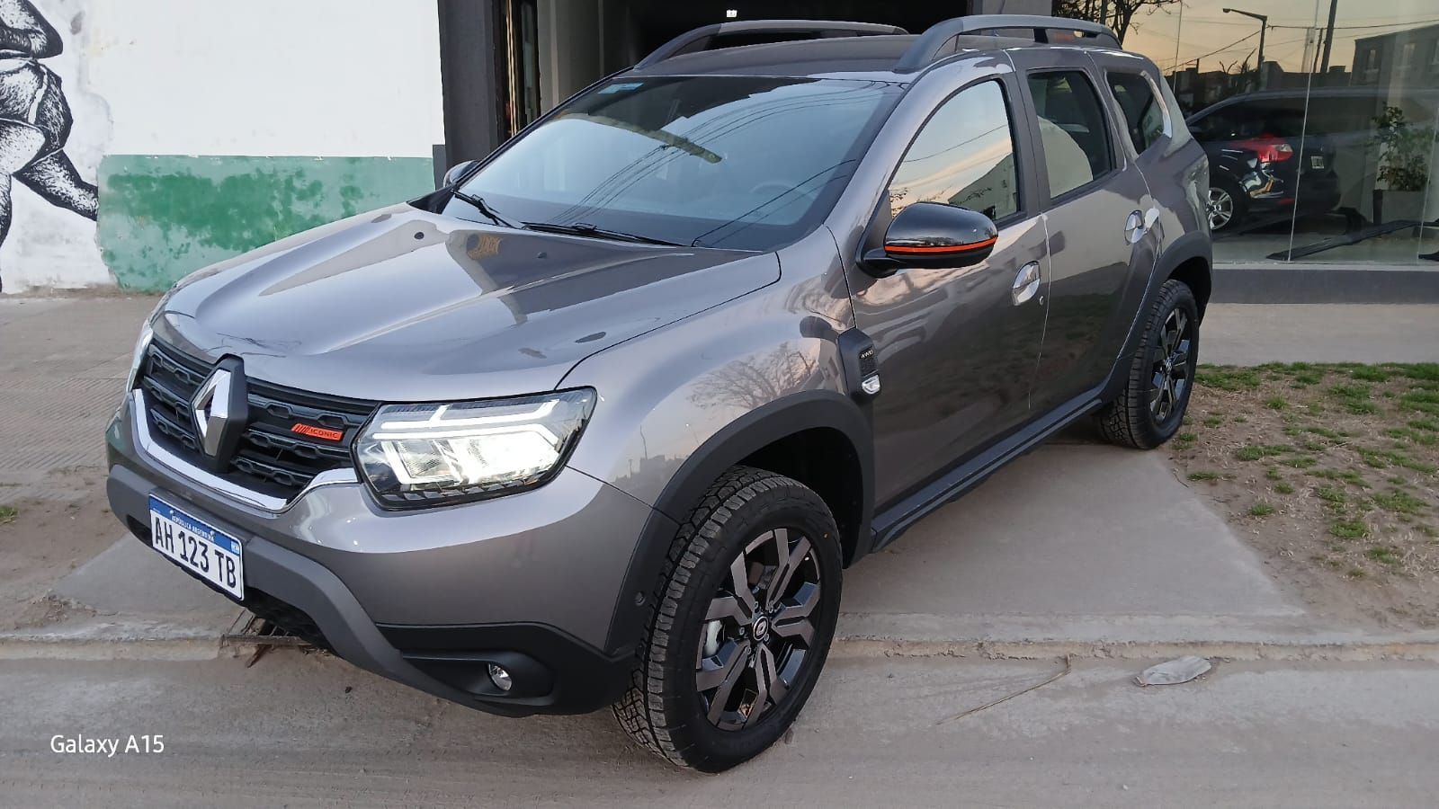 Vehículo utilitario deportivo Renault Duster de color gris estacionado frente a un edificio.
