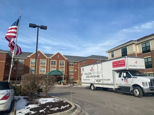 Moving truck outside a brick building with US flag. The truck has the company logo 