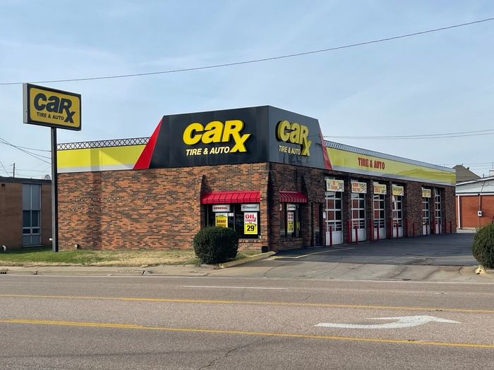 CarX Tire & Auto shop exterior with yellow and black sign, brick building, and garage bays.