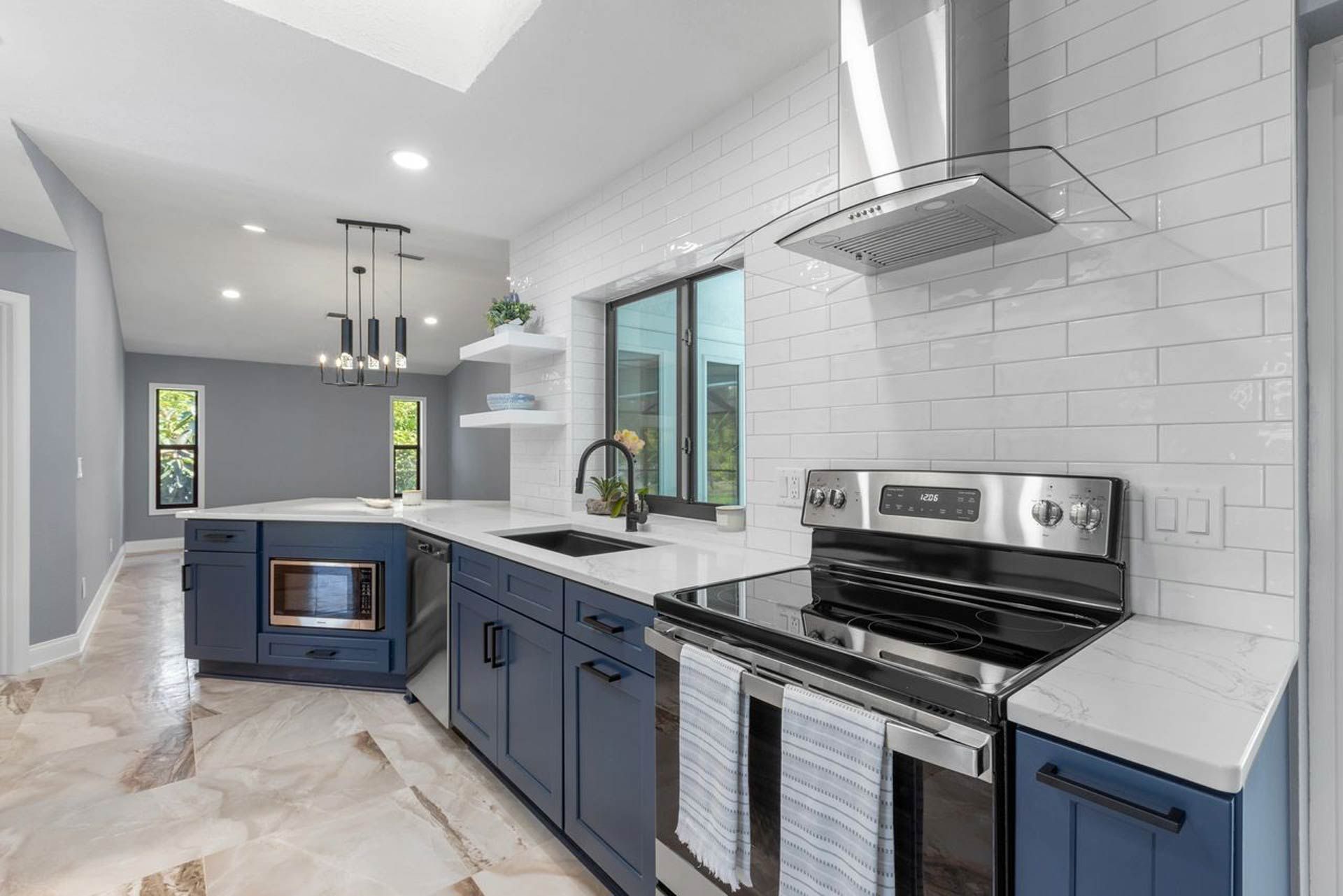 A kitchen with blue cabinets, stainless steel appliances, a stove and a sink