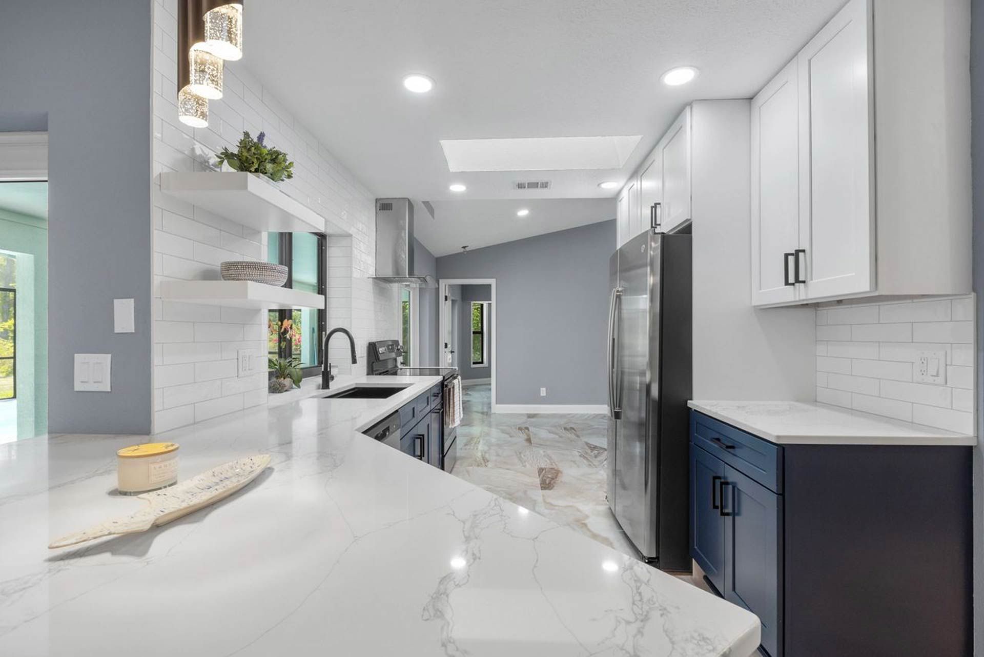 A kitchen with white cabinets and blue cabinets and a marble counter top