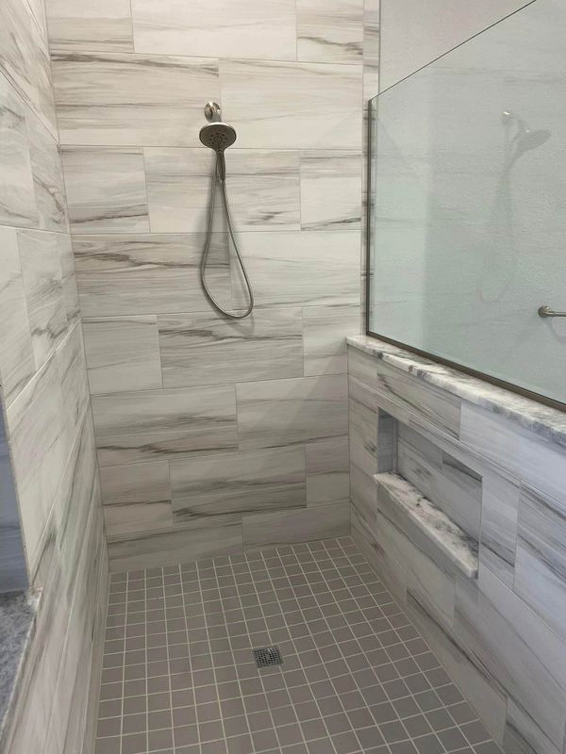 A bathroom with a walk in shower and a glass door