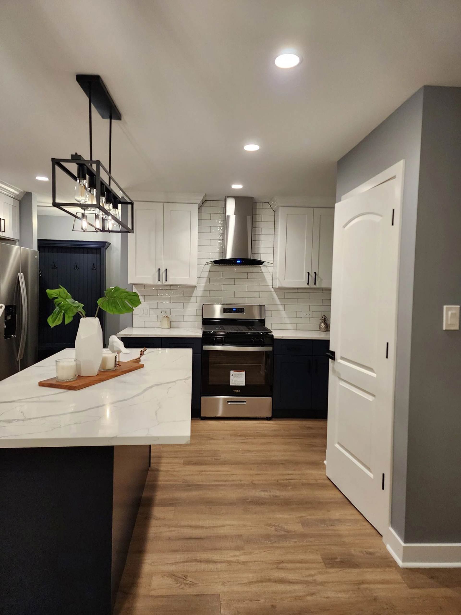 A kitchen with blue cabinets, white counter tops, a stove and a refrigerator