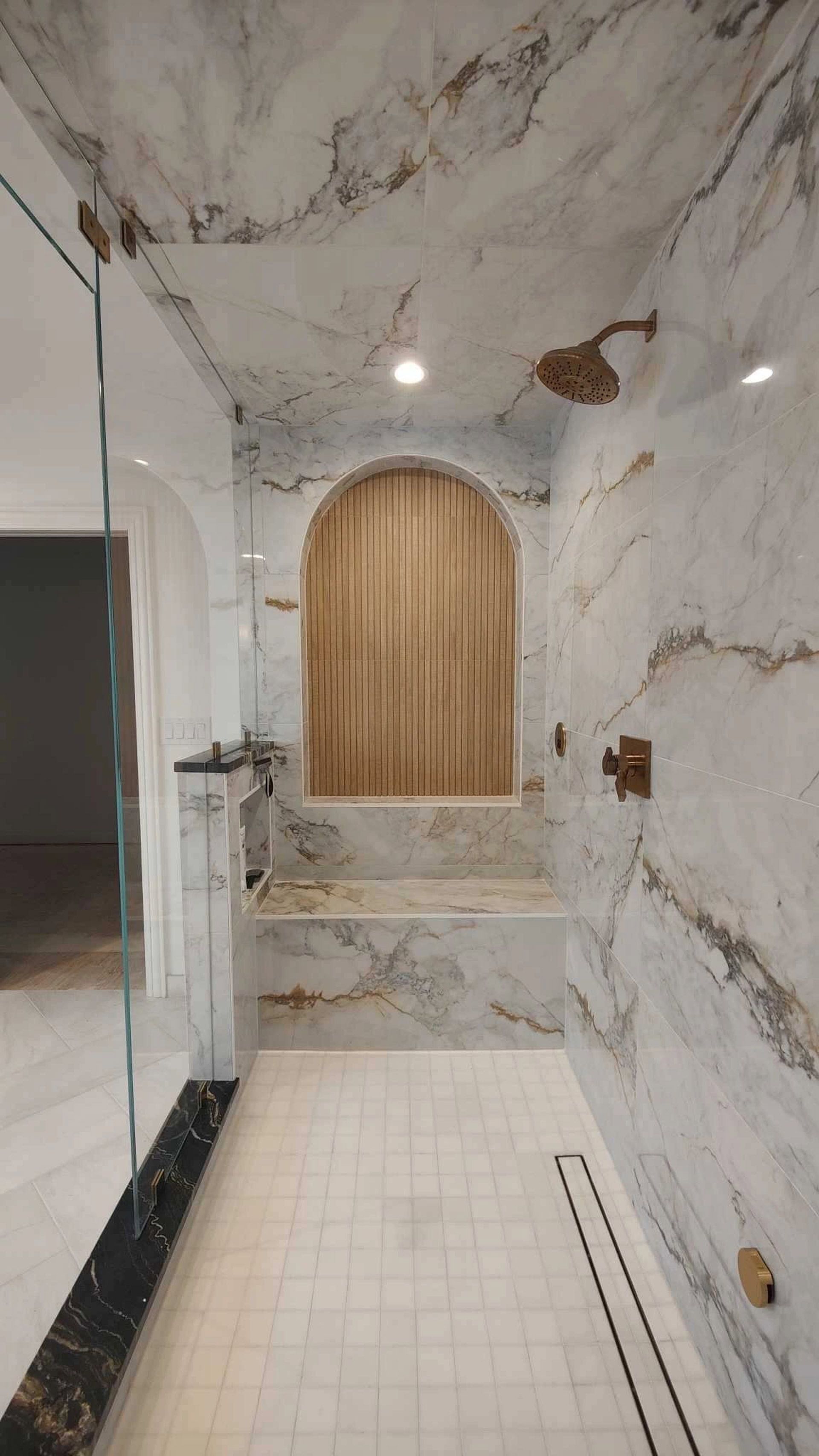 A bathroom with marble walls and a walk in shower