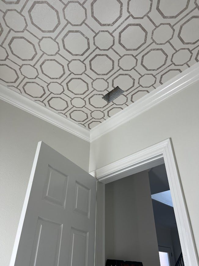 Gray patterned ceiling, white molding, doorway with open white door.