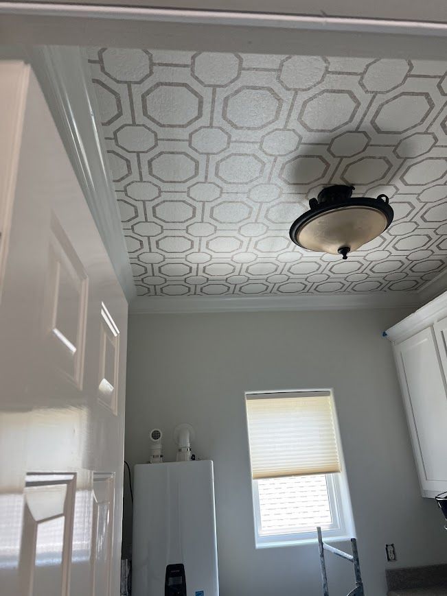 White kitchen with patterned ceiling, light fixture, window, and appliances.