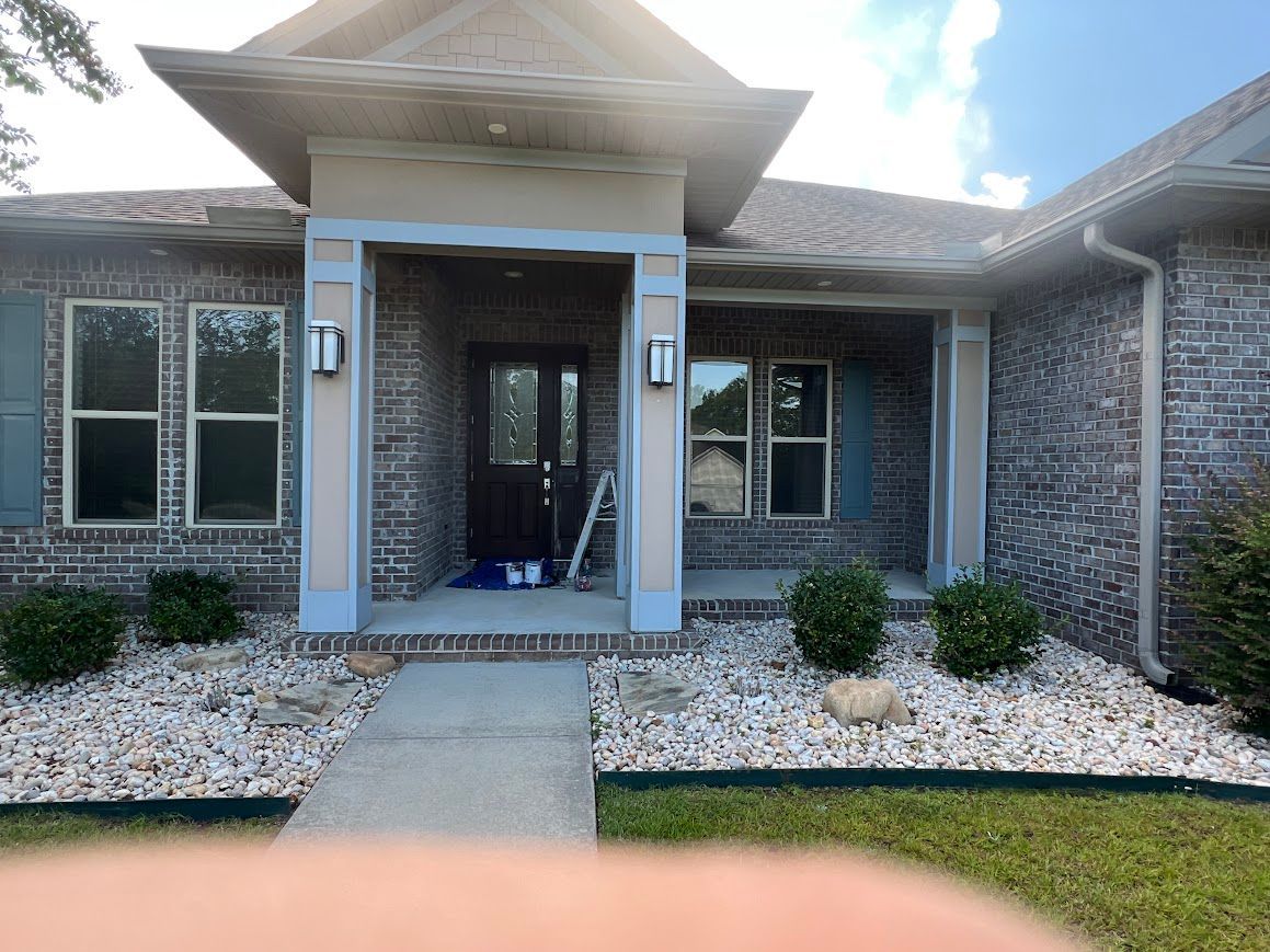 Brick house with a covered front porch, white rock landscaping, and blue shutters.