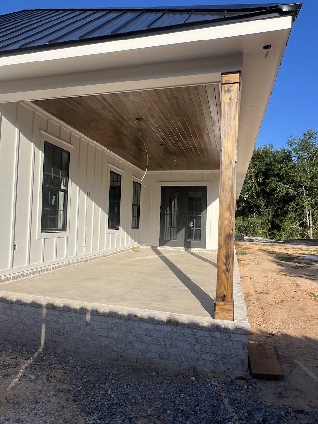 Covered porch with wood ceiling and support beams, white siding, dark trim, and a concrete patio.