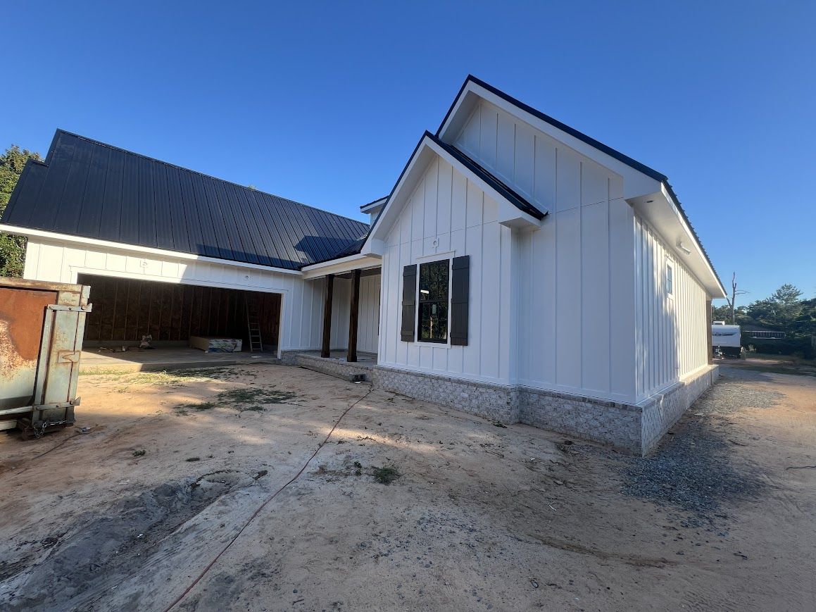 White house under construction with black roof, light blue sky.