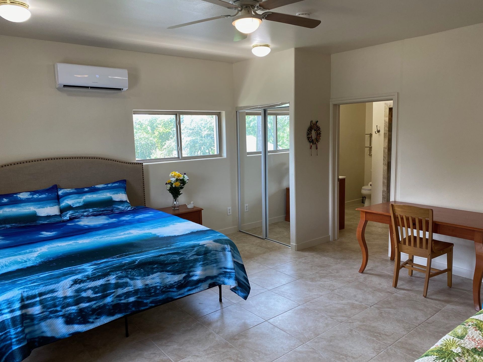 A bedroom with a bed , desk , chair and ceiling fan.