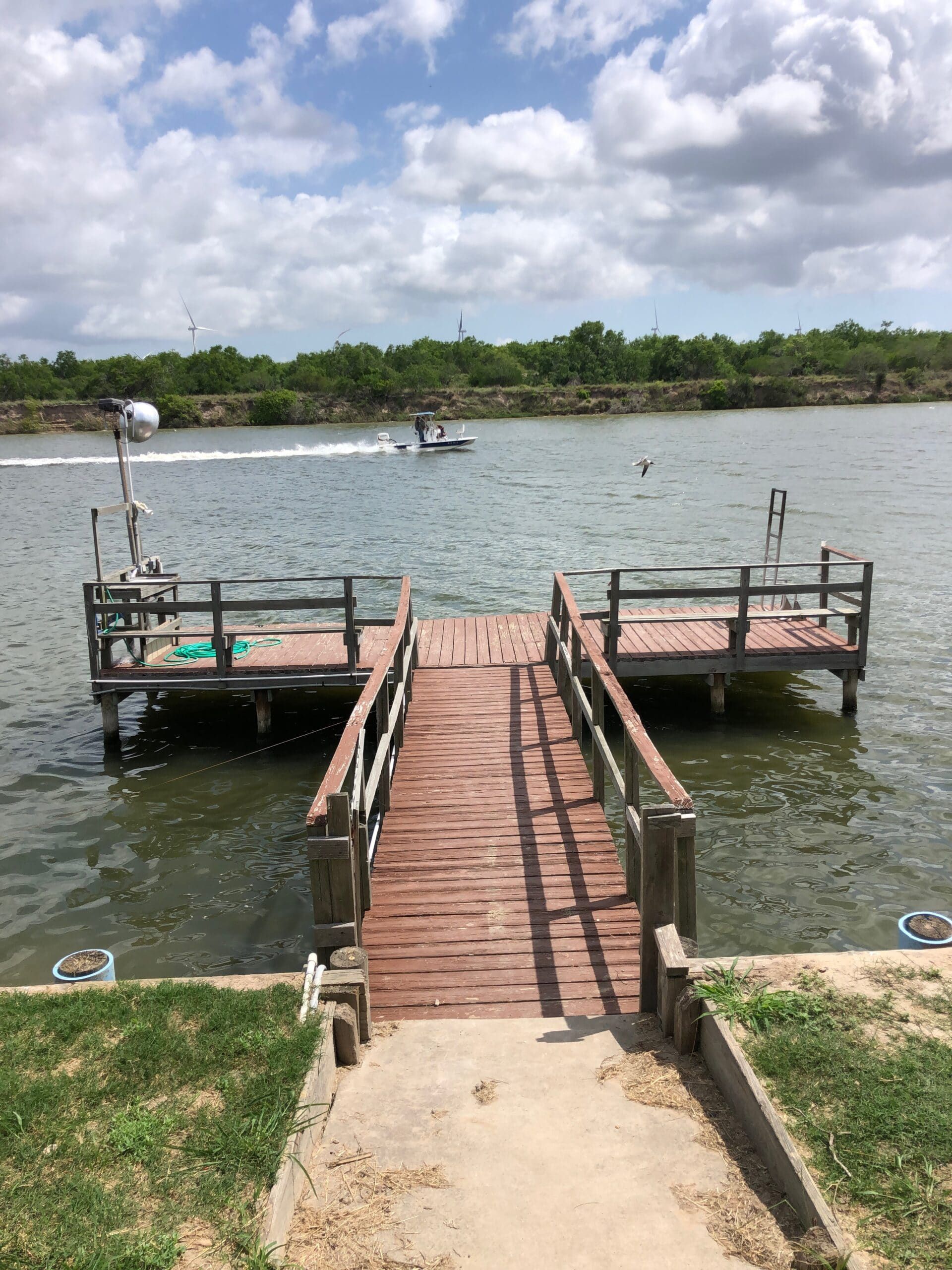 A wooden dock leading to a body of water with a boat in the background