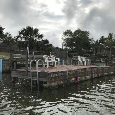 A dock with chairs and tables on it in the middle of a body of water.