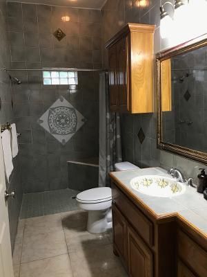 A bathroom with a toilet , sink , mirror and shower.