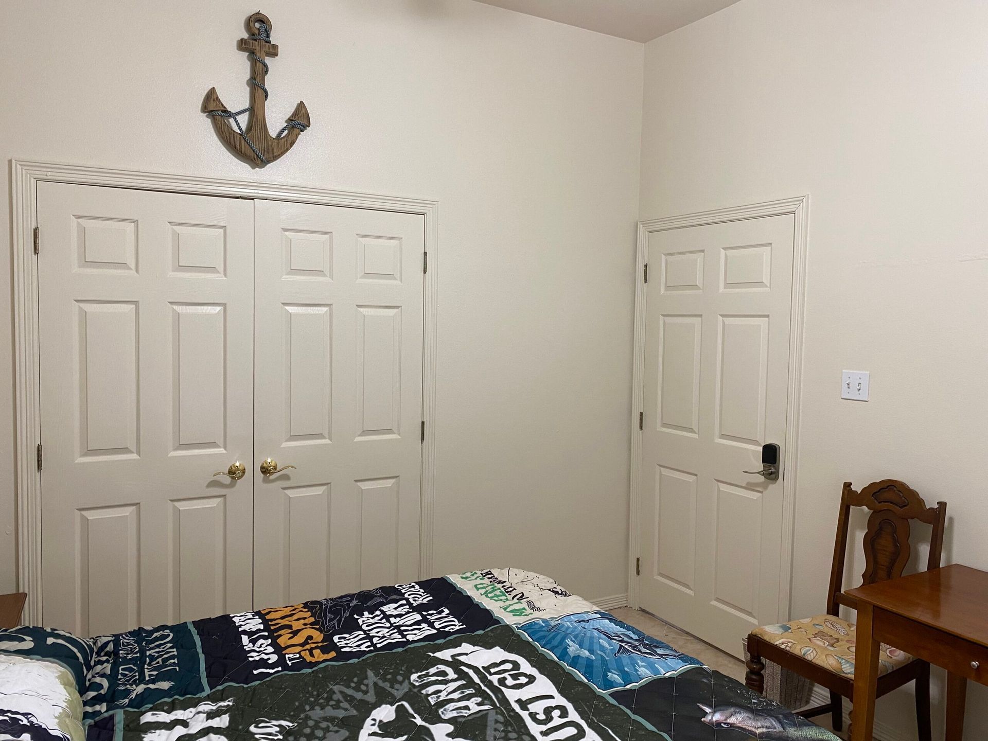 A bedroom with a bed , chair , closet and anchor on the wall.