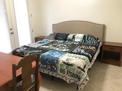 A bedroom with a bed , two nightstands , a table and a chair.