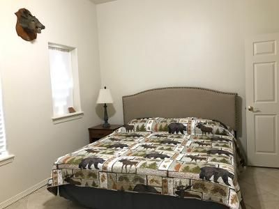 A bedroom with a bed , nightstand , lamp and a deer head on the wall.