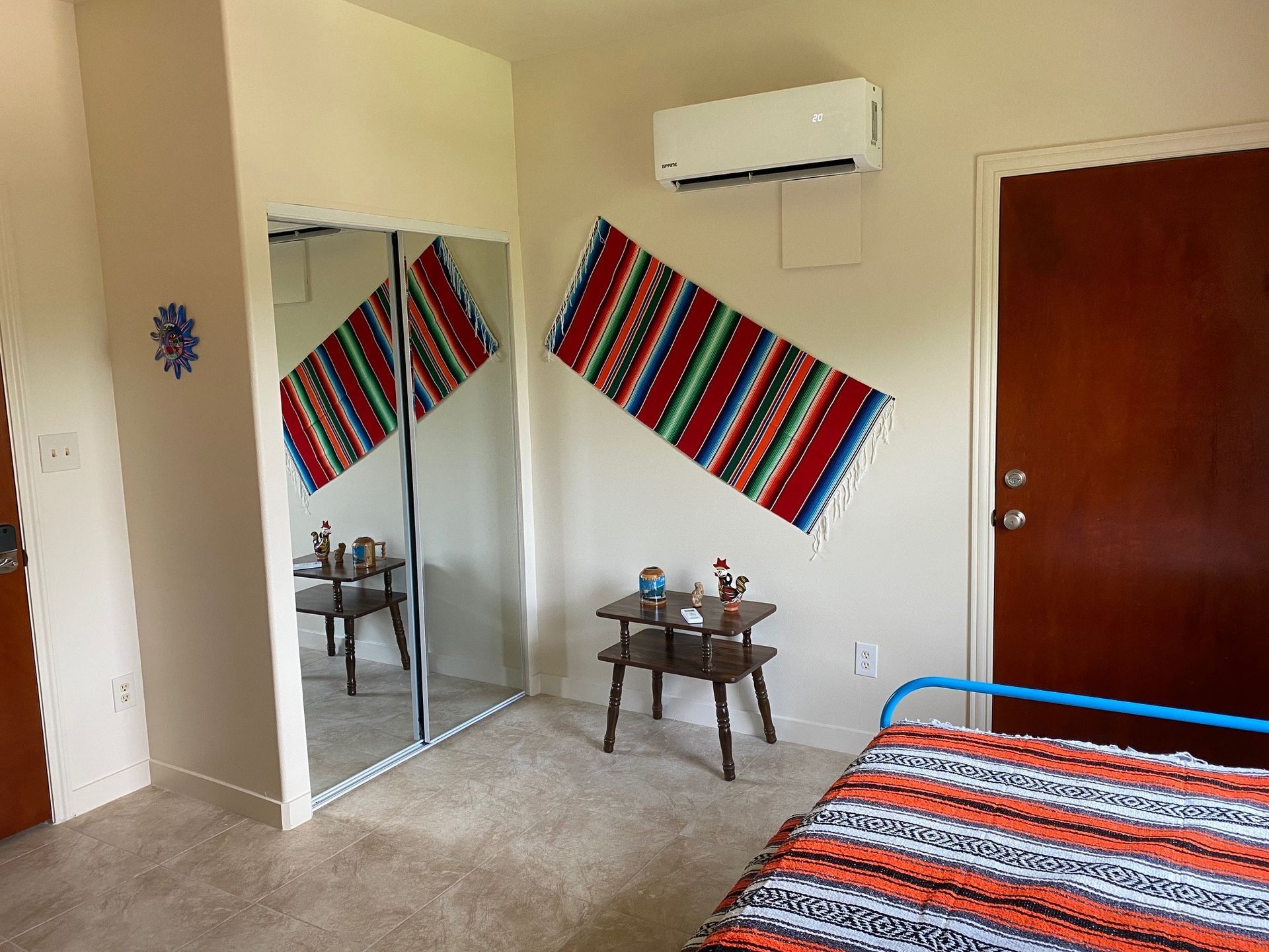 A bedroom with a bed , mirror and air conditioner.