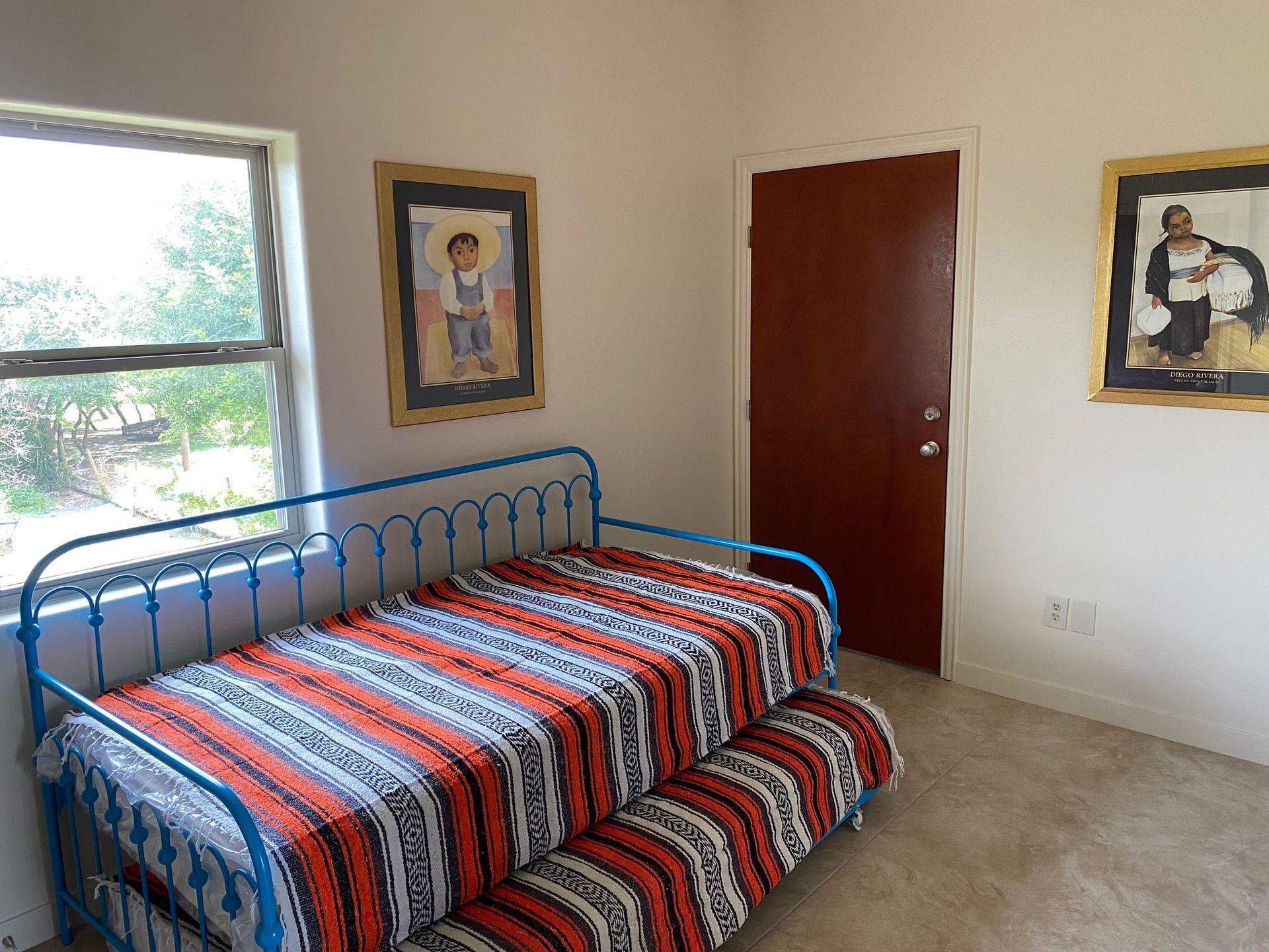 A bedroom with two beds and two pictures on the wall