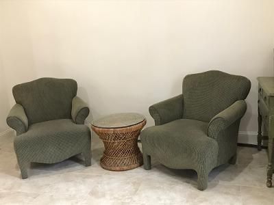 Two green chairs and a wicker table in a living room.