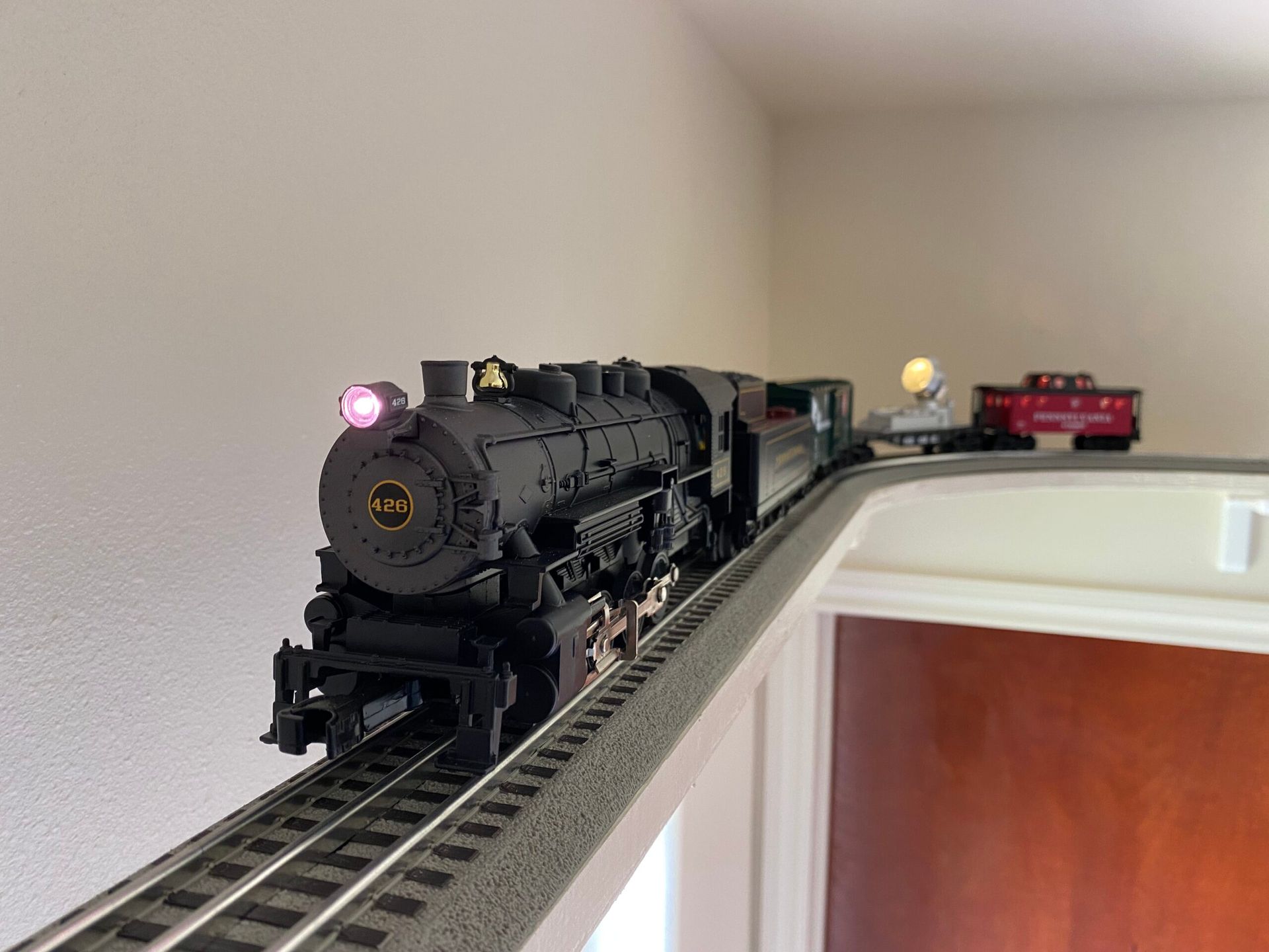 A model train is on the tracks in a room.