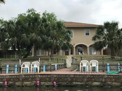 A large house with a dock and chairs in front of it.