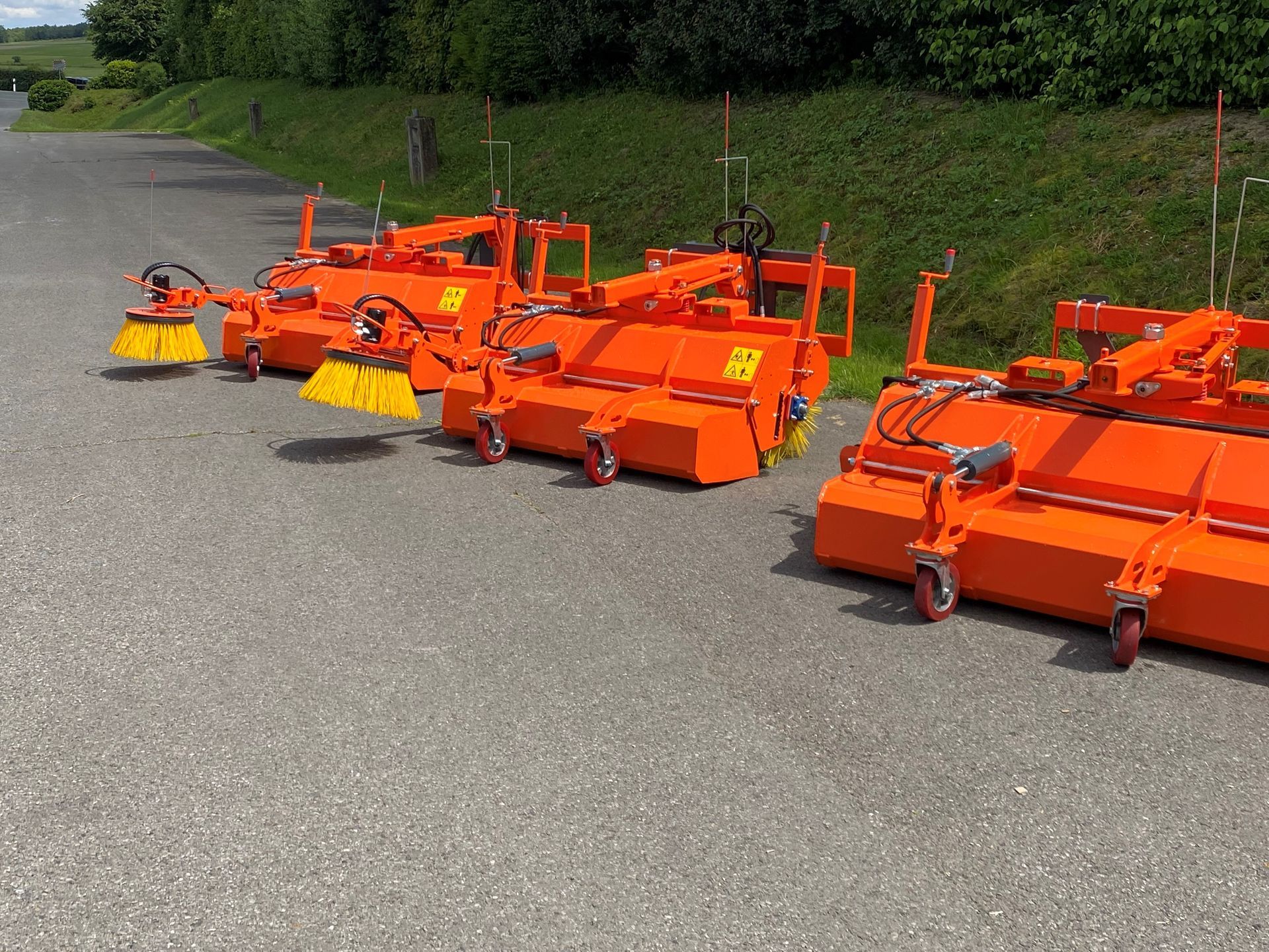 Eine Reihe orangefarbener Besen steht am Straßenrand