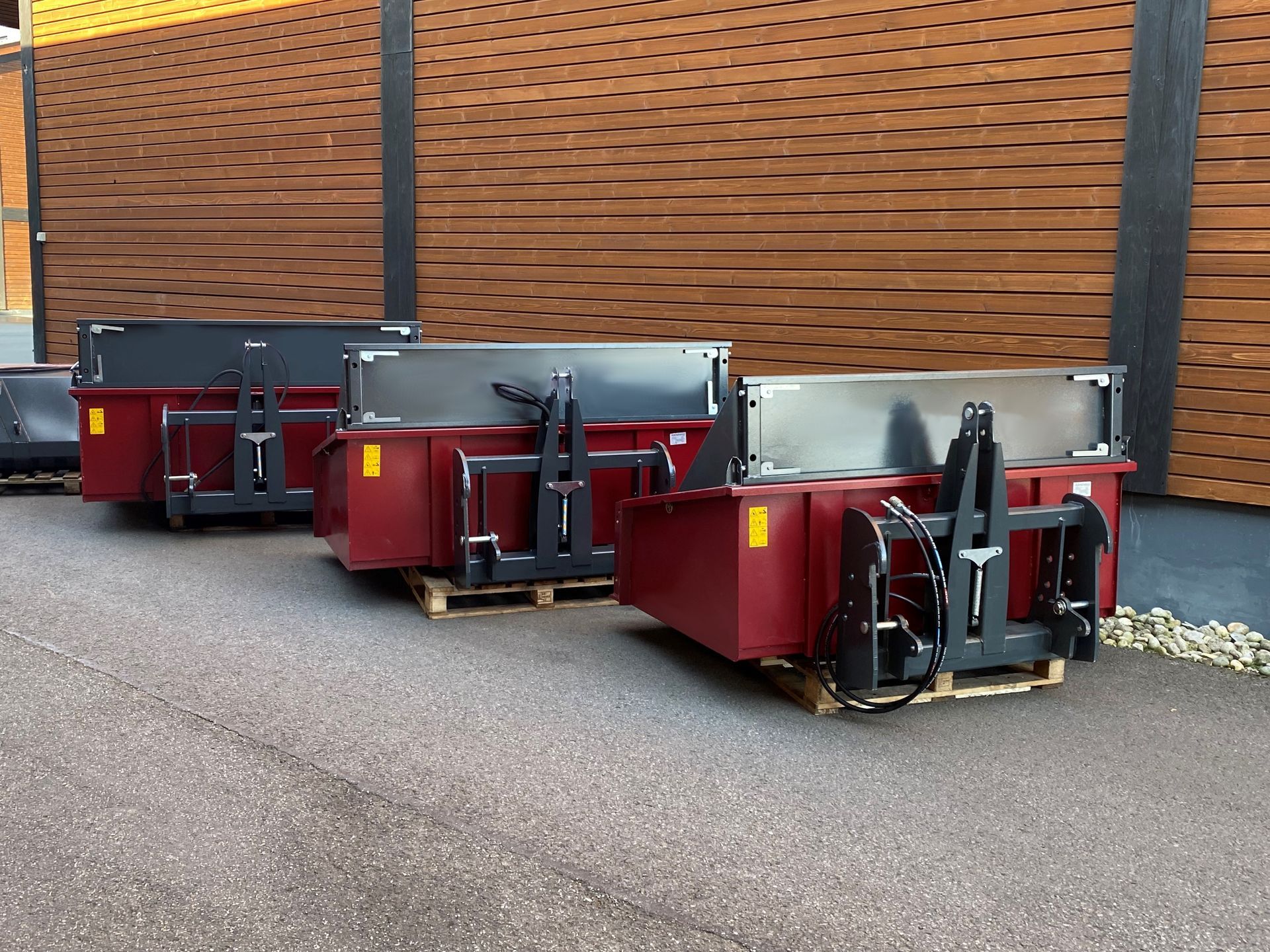 Vor einem Gebäude steht eine Reihe roter Müllcontainer.