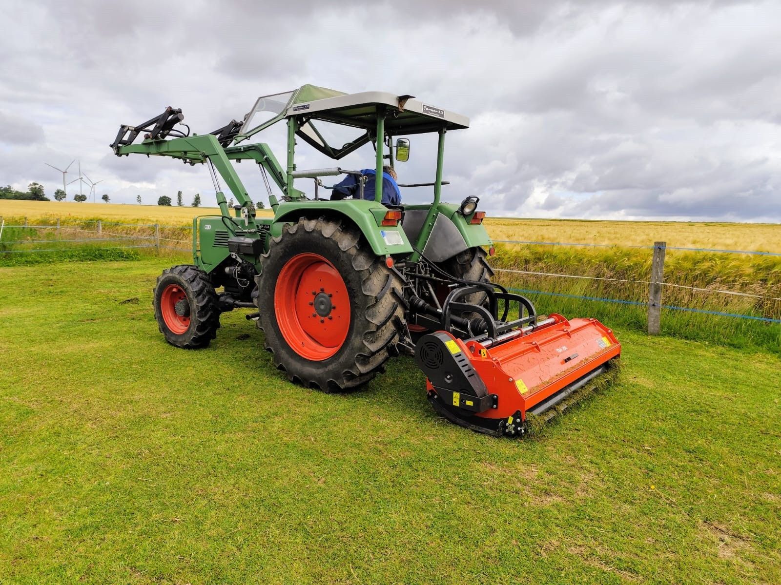 Ein grün-roter Traktor steht auf einer Wiese.