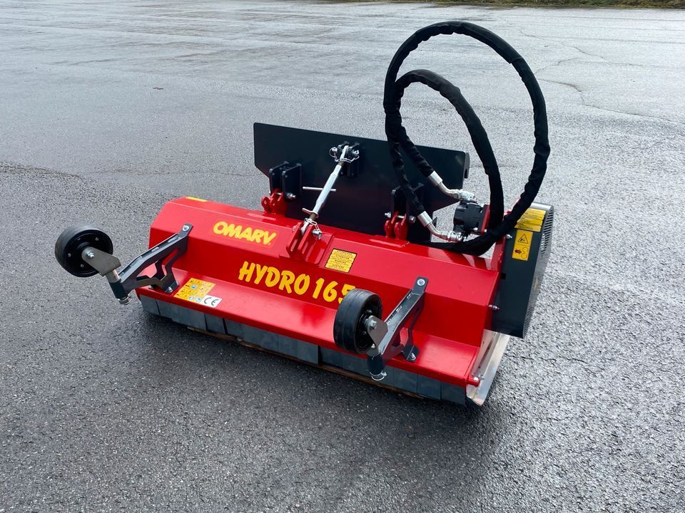 Ein gelber Rasenmäher ist an der Rückseite eines Traktors befestigt