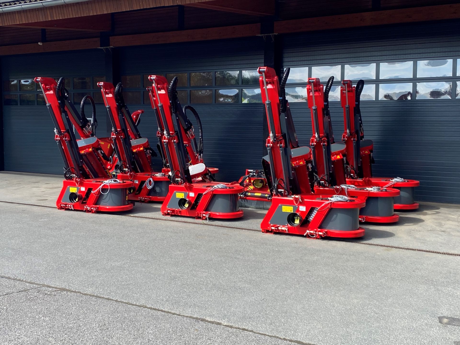 Eine Reihe roter Traktoren steht vor einem Garagentor