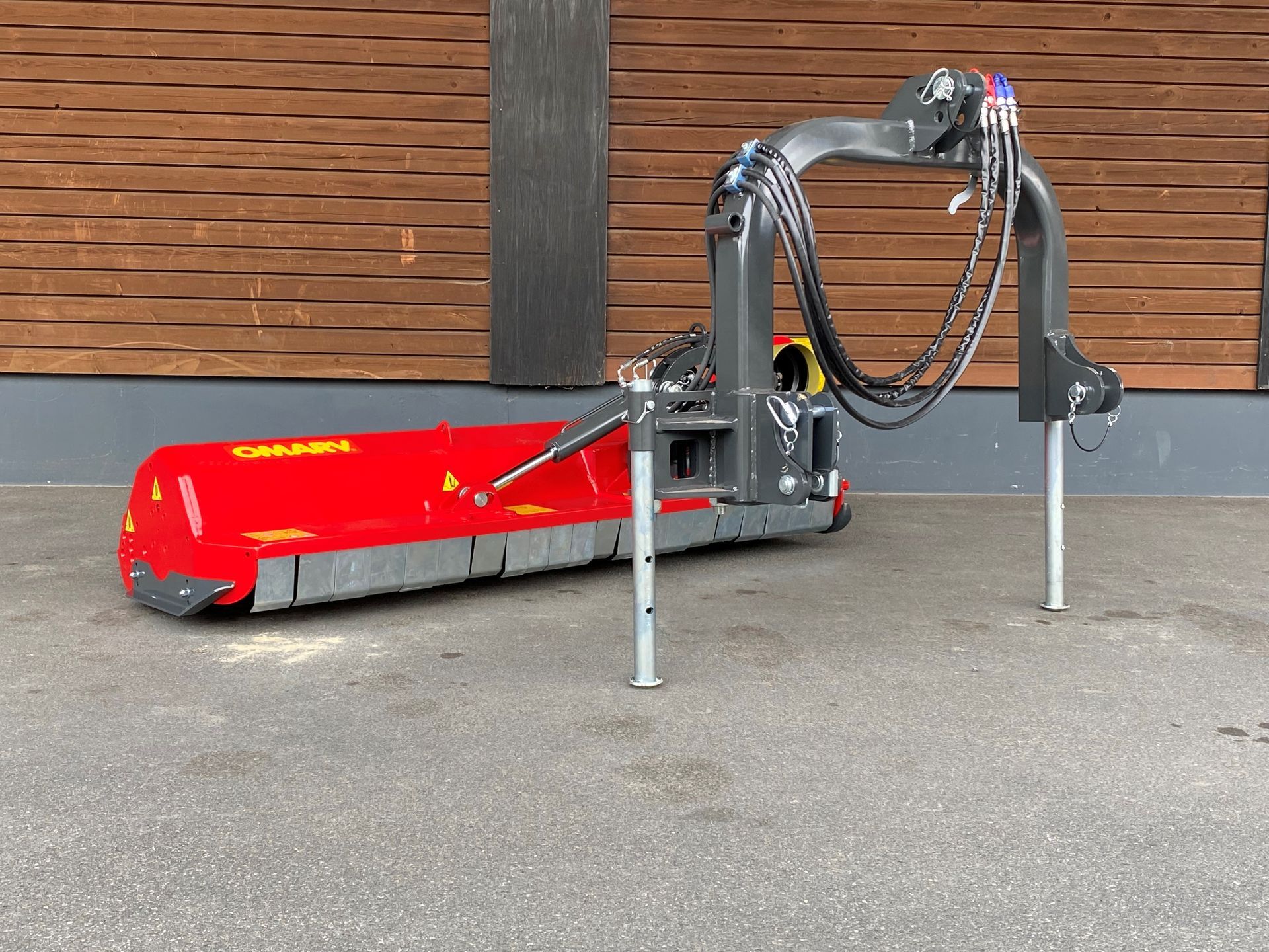 Eine rot-schwarze Maschine steht vor einem Holzgebäude.