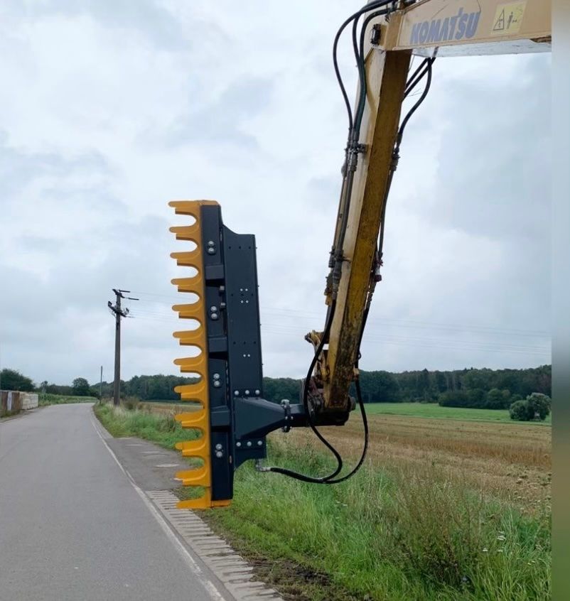 Ein gelber Rasenmäher ist an der Rückseite eines Traktors befestigt