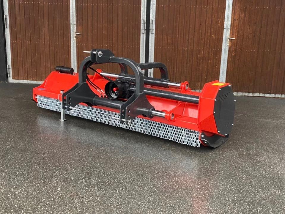 Vor einem hölzernen Garagentor steht eine rot-schwarze Maschine.