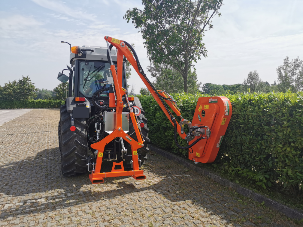 Ein gelber Traktor schneidet auf einem Feld einen Baumstumpf ab.