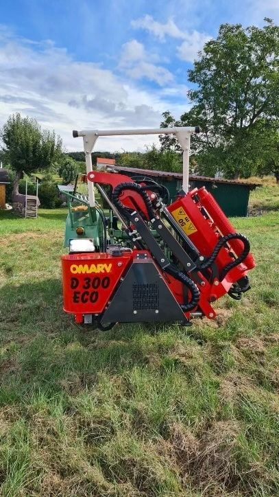 Eine rot-schwarze Maschine steht mitten auf einer Wiese.