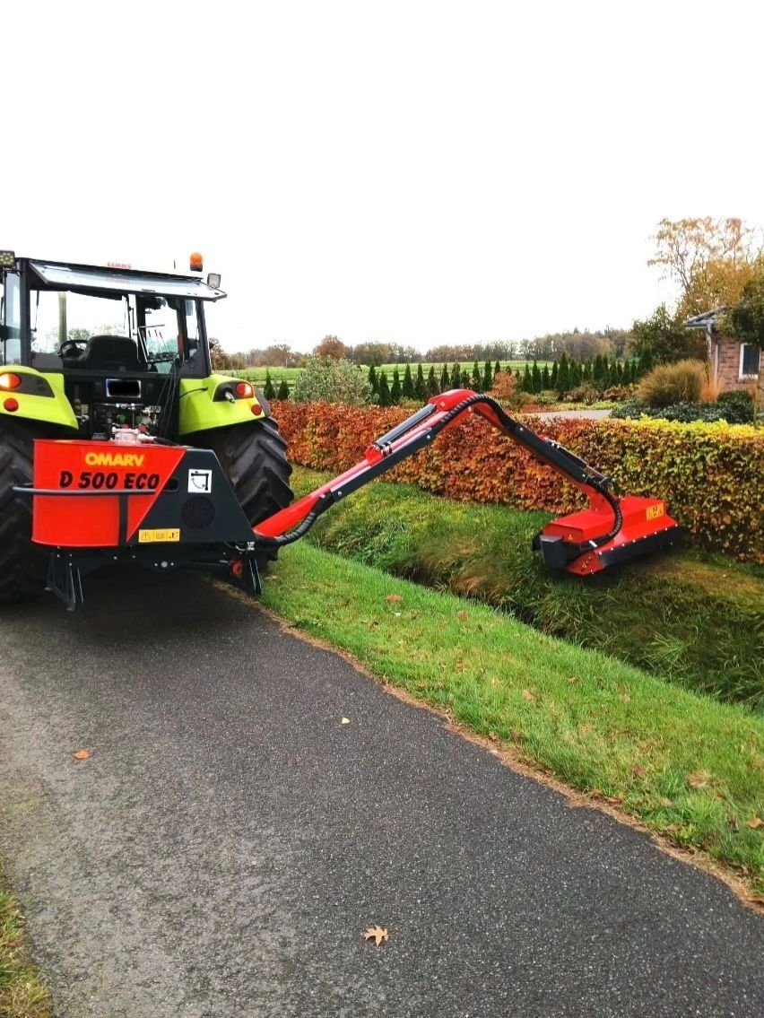 Ein Traktor schneidet Gras am Straßenrand.
