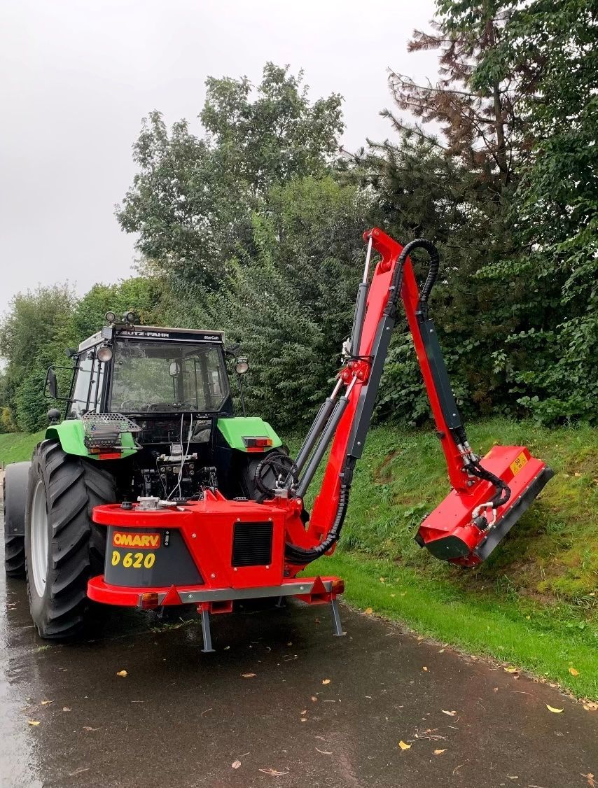 Ein rot-schwarzer Traktor steht am Straßenrand