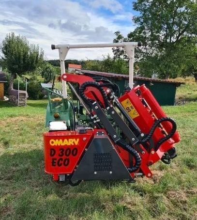 Ein roter Omary D300 Öko-Traktor ist auf einer Wiese geparkt